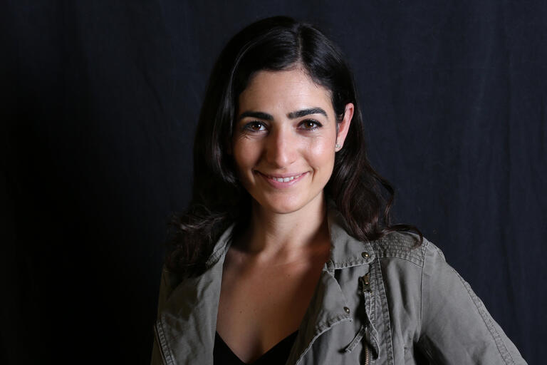 woman smiling in front of a dark background 