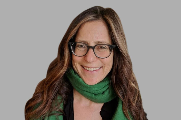 headshot of a woman with glasses in a green scarf