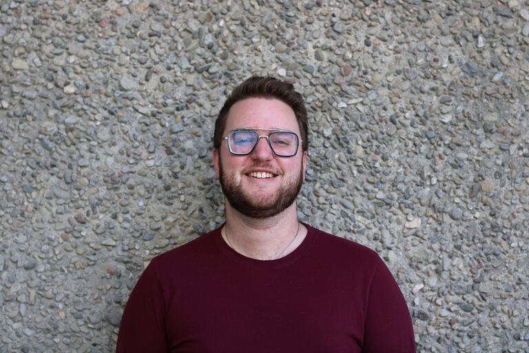 Man with red sweater and glasses smiling into the camera