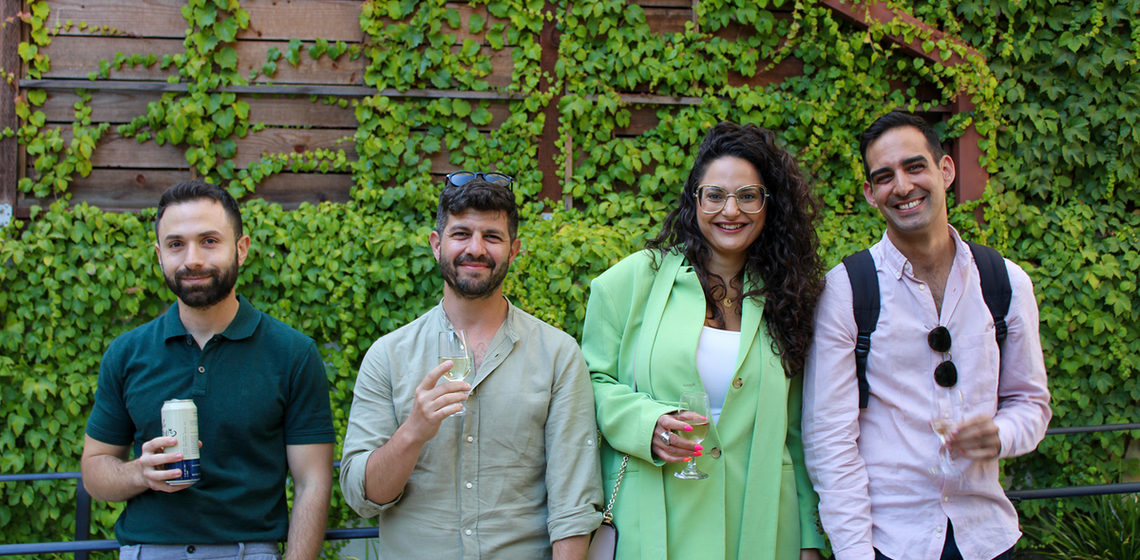 four people in front of a verdant background smiling at the camera