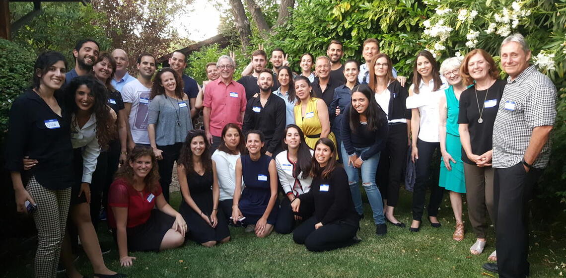 large group of students standing in a green backyard smiling at the camera
